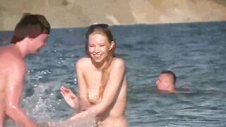 A mature woman gets undressed on the beach and plays with seagulls