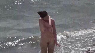 Nudist couple enjoy each other in a sensual way on the beach