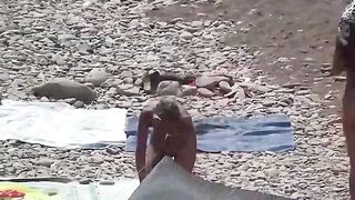 Nudist couple enjoy each other in a sensual way on the beach