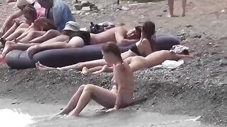 Nudist couple enjoy each other in a sensual way on the beach