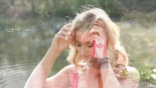 A blonde girl caresses herself on the shores of the lake