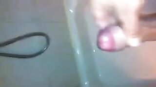 The kid caresses his dick under the shower with his hand