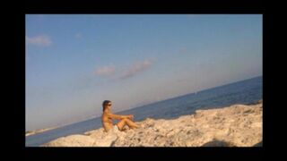 A naked girl is basking in the sun on the beach