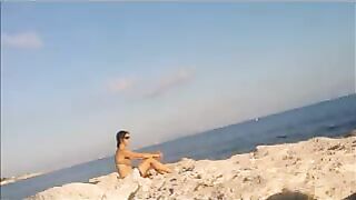 A naked girl is basking in the sun on the beach