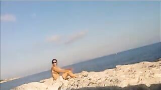 A naked girl is basking in the sun on the beach