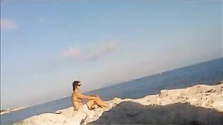 A naked girl is basking in the sun on the beach