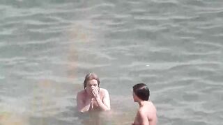 Two naked girls playing in the sea, getting wet and enjoying themselves