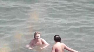 Two naked girls playing in the sea, getting wet and enjoying themselves