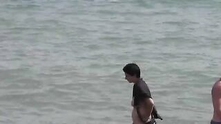Two naked girls playing in the sea, getting wet and enjoying themselves