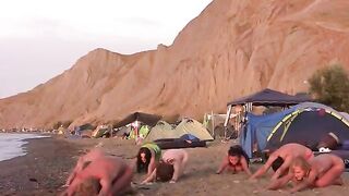 A group of naked people play volleyball on the sandy beach