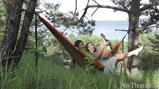 A lesbian beauty gives herself a tan on the nature backdrop