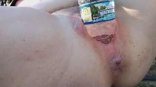 A busty MILF pees in a bottle and masturbates outside, reaching intense pleasure